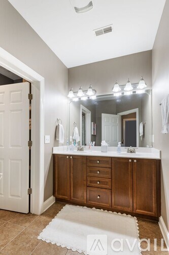 A bathroom with a vanity, mirror, and lights.
