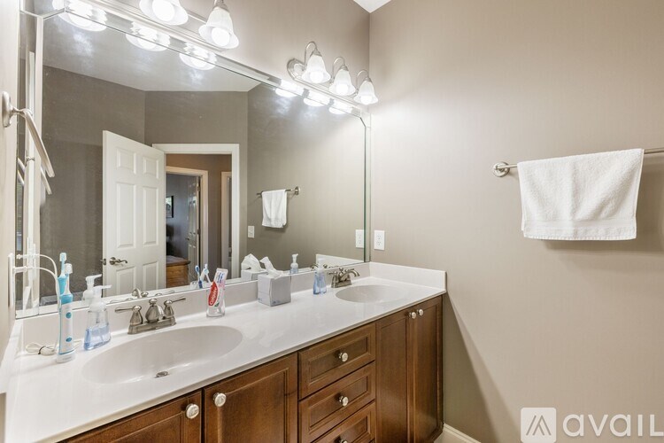 A bathroom with a double sink vanity and a mirror with lights above it.
