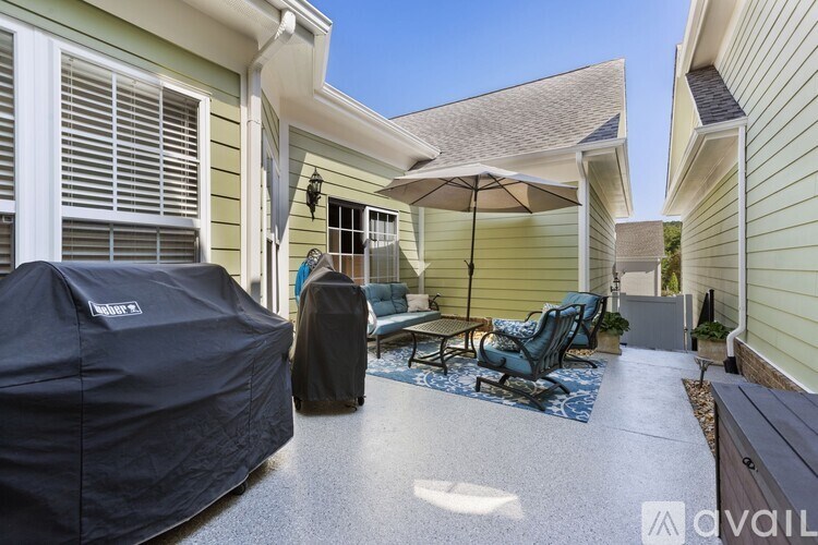 A patio with a table and chairs and a covered grill.