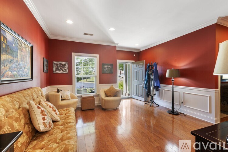 A living room with a sofa, armchairs, and a table with a lamp.