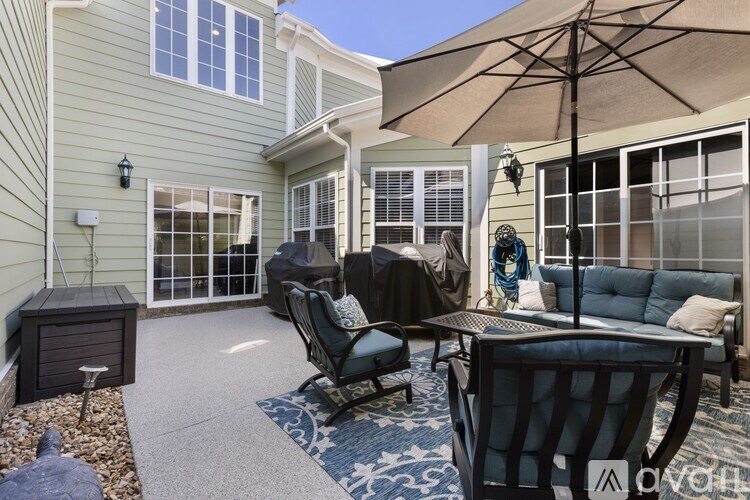 A patio with a table, chairs, and an umbrella.