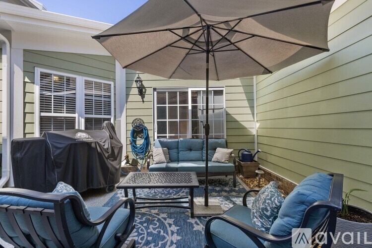 A patio with a table, chairs, and an umbrella.
