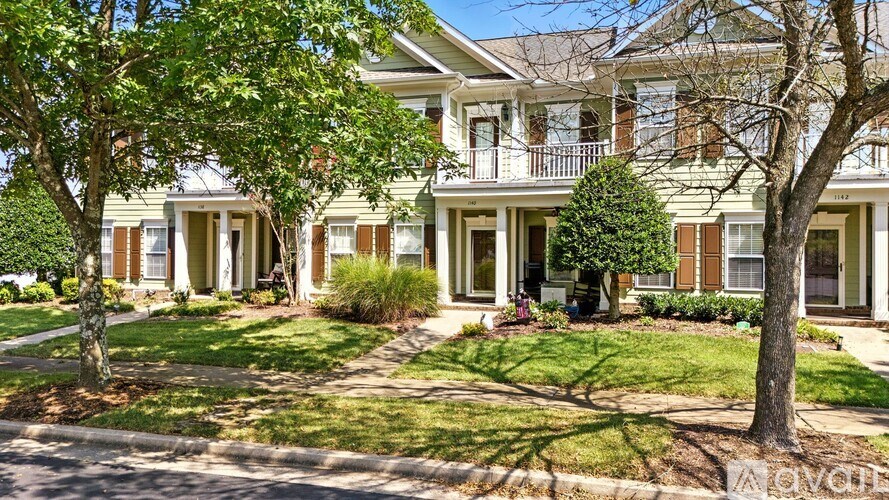 A row of houses with green lawns and trees.