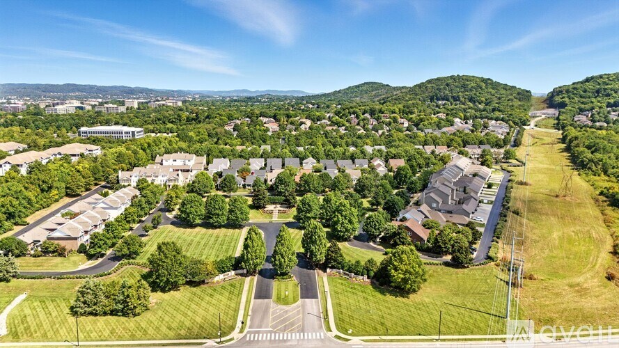 A bird's eye view of a residential area with houses, trees, and a road.