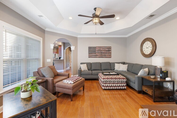 A living room with a grey couch, a coffee table, and a ceiling fan.