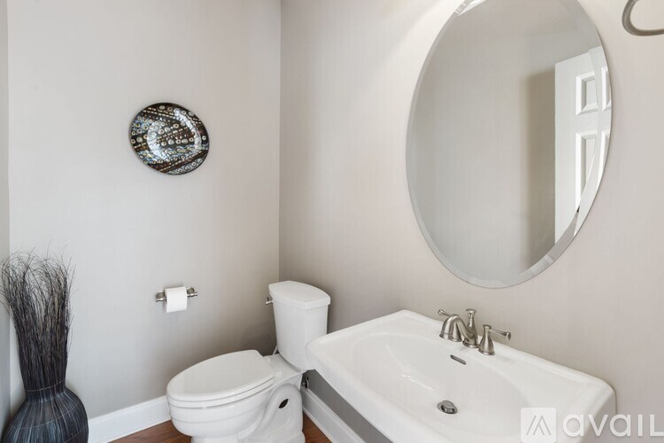 A bathroom with a toilet, sink, and mirror.