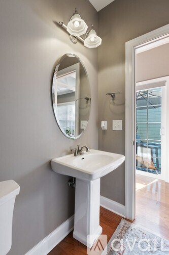 A bathroom with a white sink and a round mirror above it.