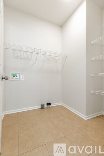 A small, empty room with a door and a wall-mounted shelf.