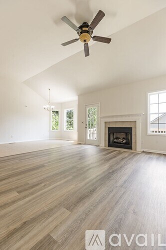 A spacious living room with a fireplace and a ceiling fan.
