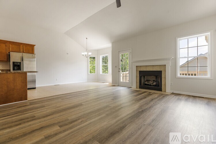 A spacious living room with wood flooring and a fireplace.