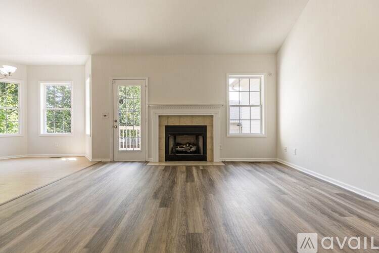 A spacious room with a fireplace and wooden flooring.