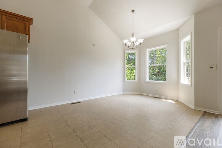 A large, empty room with a stainless steel refrigerator on the left side.