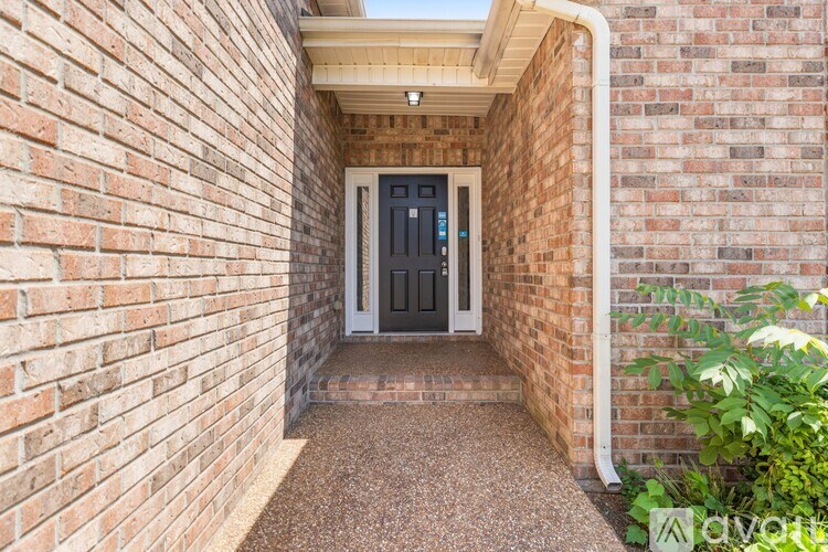 A brick wall with a door and a plant in front.