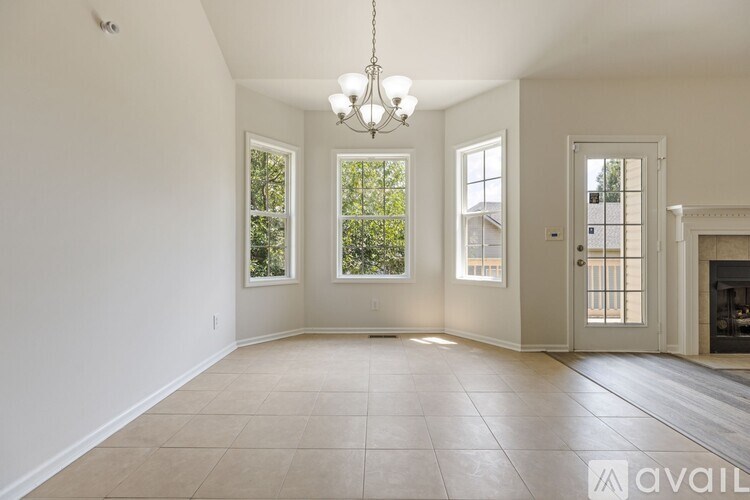 A spacious room with a chandelier, tiled floor, and three windows.