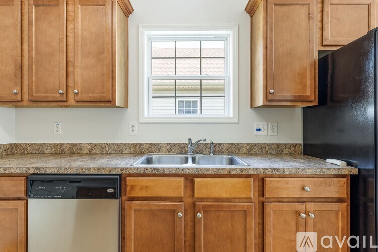 A kitchen with wooden cabinets and a black refrigerator.