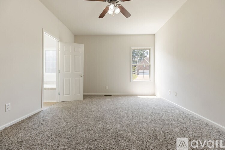 A room with a ceiling fan and carpeted floor.