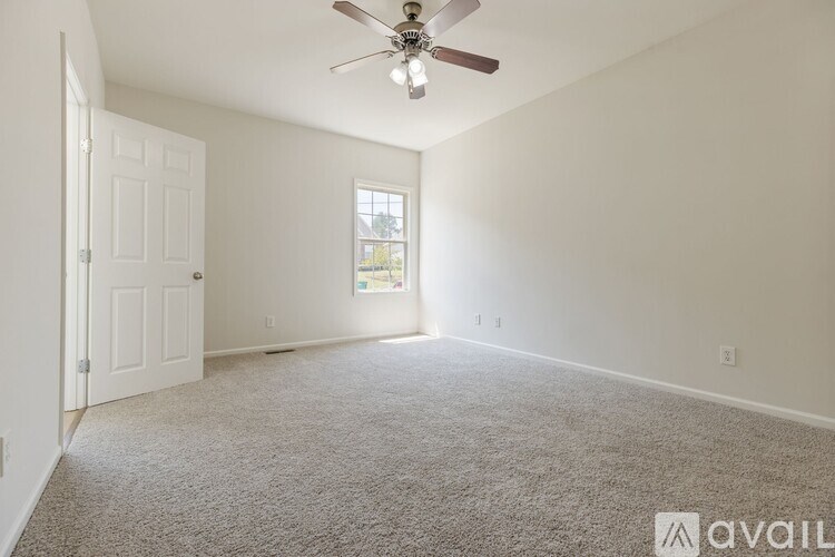 A room with a ceiling fan and carpeted floor.