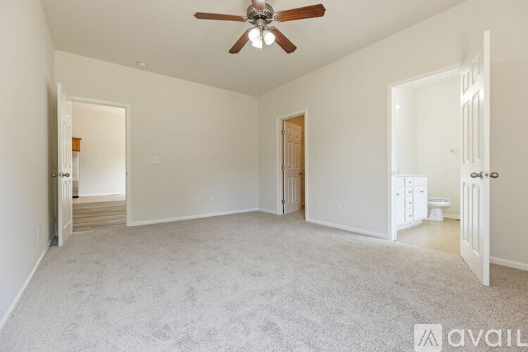 A spacious room with a ceiling fan and carpeted floor.