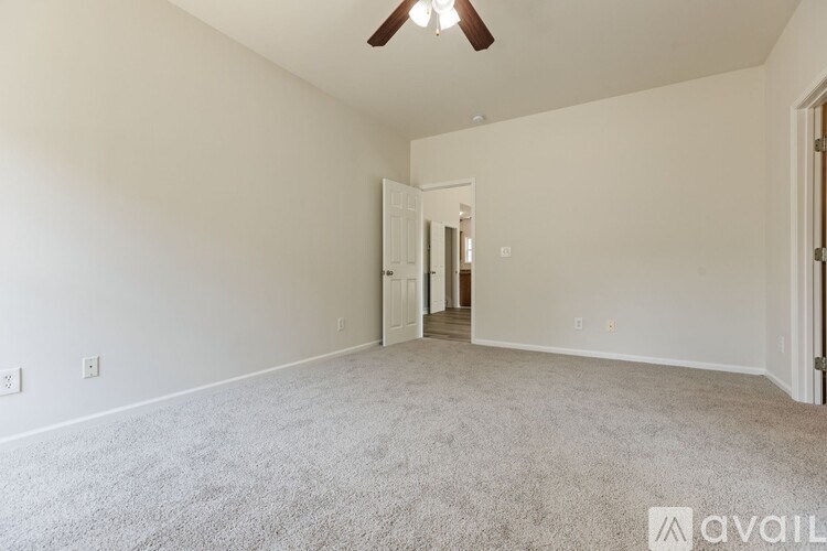 A spacious room with a carpeted floor and a ceiling fan.