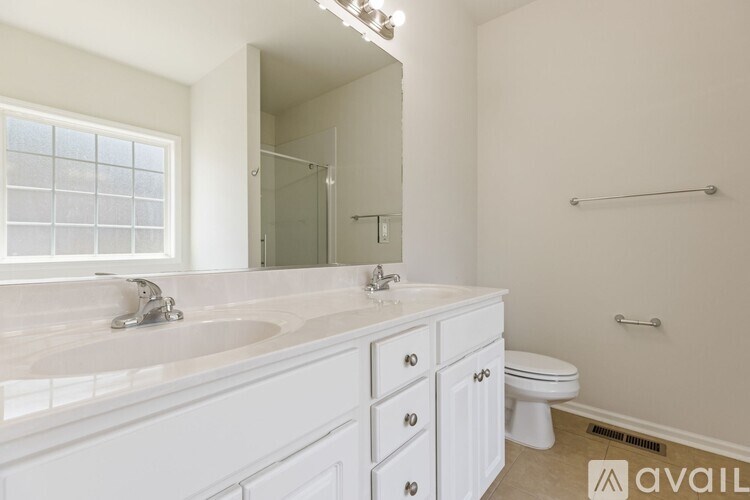 A bathroom with a sink, toilet, and a window.