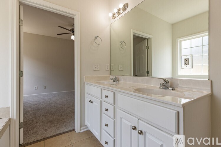 A bathroom with a vanity, mirror, and a fan.
