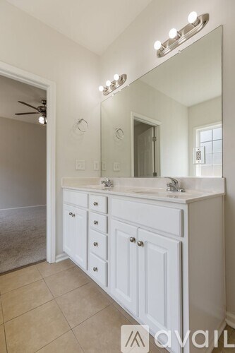 A bathroom with a vanity, mirror, and lights.