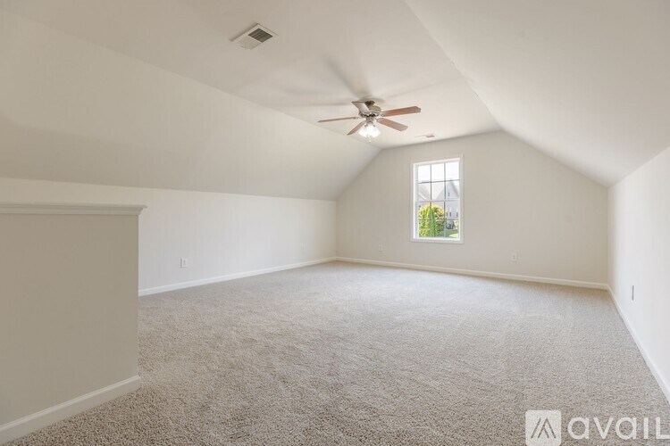 A room with a carpeted floor, a ceiling fan, and a window with a view of trees outside.