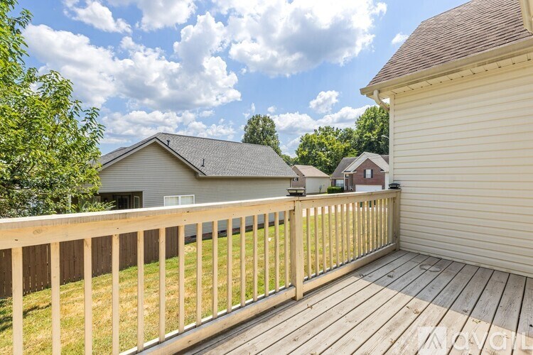 A wooden deck with a railing and a house in the background.