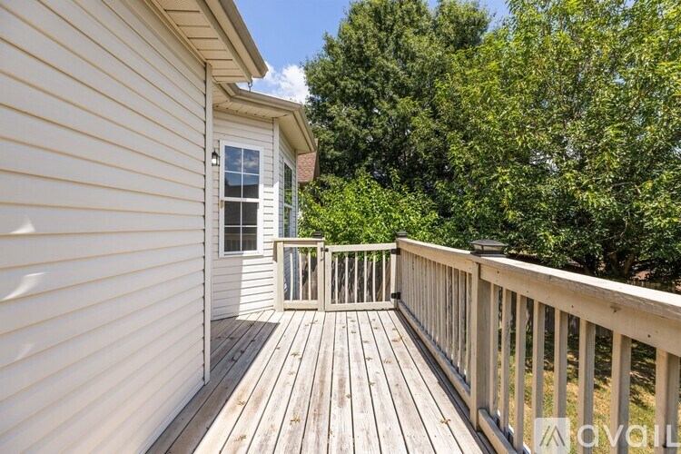 A deck with a railing and a small house with a window and a door.