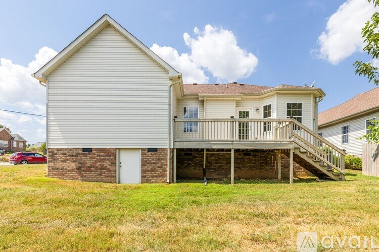 A two-story house with a white exterior and a red car parked in front.