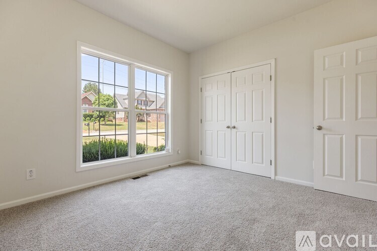 A room with a large window and a carpeted floor.