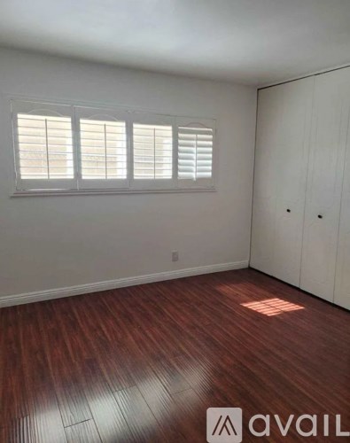 A room with wooden flooring and a window with blinds.