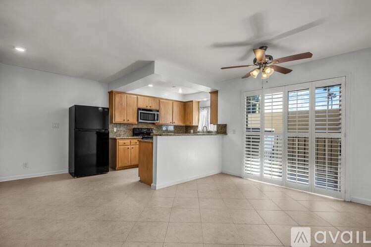 A kitchen with wooden cabinets and a black fridge is available for rent.