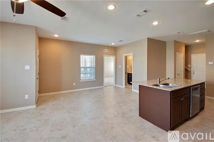 A spacious living room with a kitchen area in the background.