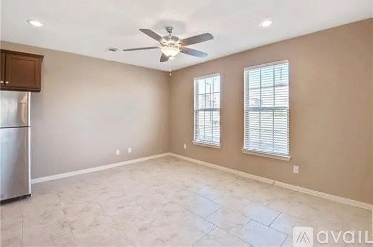 A spacious room with a ceiling fan and two windows.
