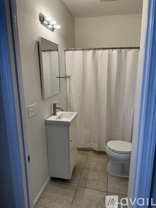 A bathroom with a toilet, sink, and shower curtain.