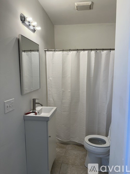 A small bathroom with a toilet, sink, and shower curtain.