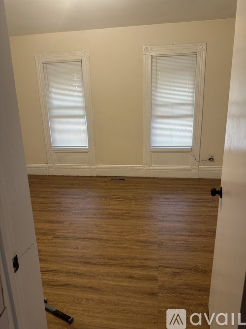 A room with wooden floors and two windows.