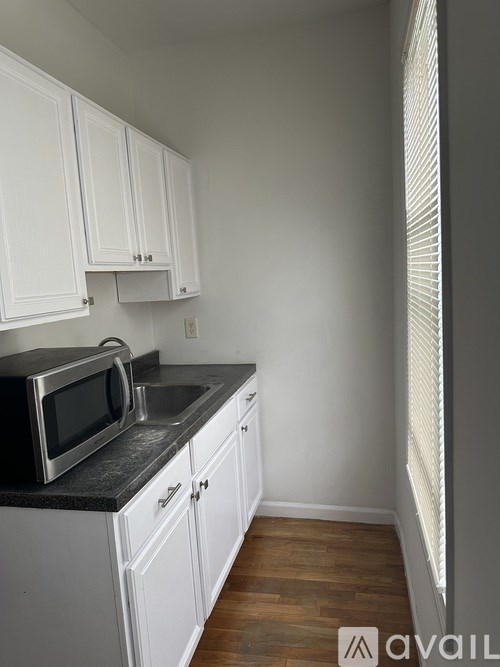 A kitchen with white cabinets and a black countertop.