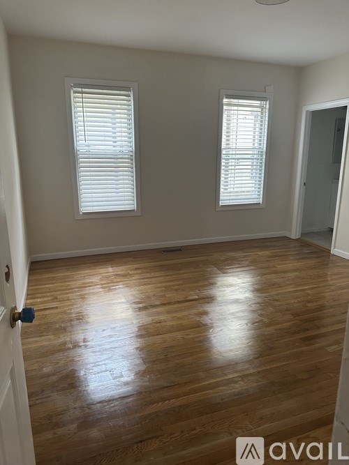 A room with wooden floors and two windows.