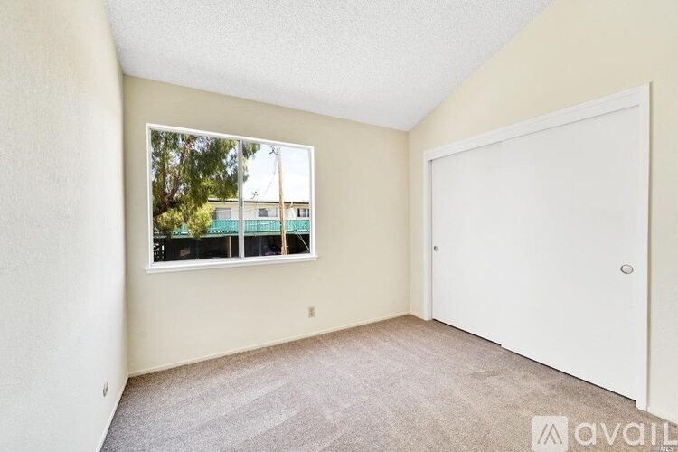 A room with a large window and a door is available for rent.