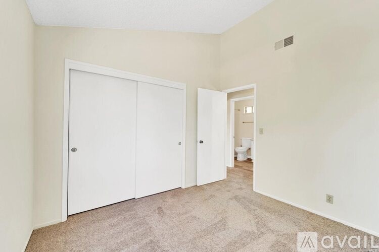 A room with a carpeted floor and two white doors.