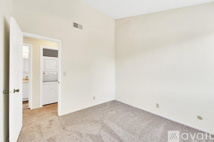 A room with a carpeted floor and a doorway leading to another room.