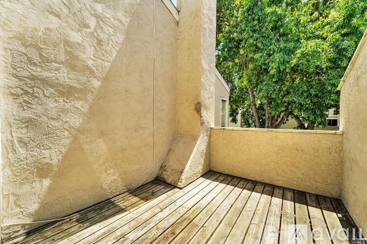 A wooden deck with a white wall and a window.