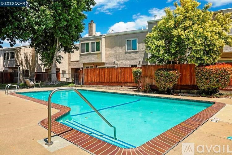 A pool surrounded by a wooden fence and a house.