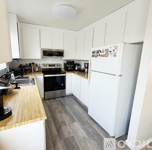 A kitchen with white cabinets and a white fridge.