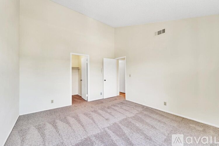 A room with a carpeted floor and two open doors.