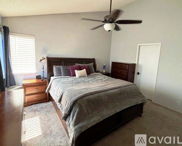 A bedroom with a large bed and a ceiling fan.