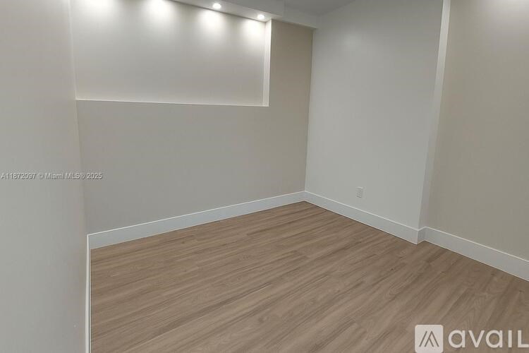 A room with wooden flooring and white walls.