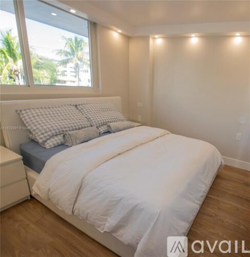 A bedroom with a large bed and a window overlooking a palm tree-filled area.